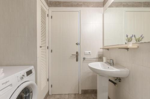 a white bathroom with a washing machine and a sink at Melissa Apartment in Alaior