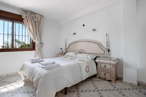 a white bedroom with a bed and a window at Casa Torremuelle in Benalmádena