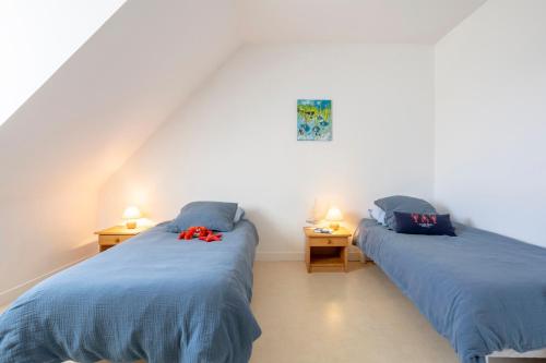two twin beds in a room with two lamps at La Pause Bigoudène in Penmarch