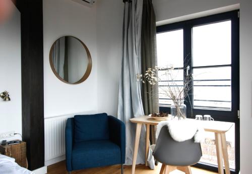 a bedroom with a blue chair and a table and a mirror at The Pines Boutique Villa in Braşov