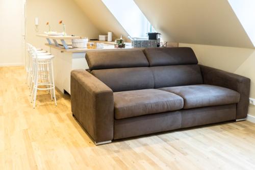 a brown couch in a living room with a kitchen at Hotel Haus Broichtal in Alsdorf