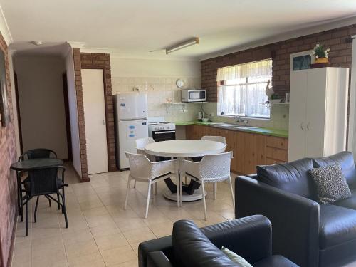 a kitchen and a living room with a table and chairs at Unit 16, 2 Casuarina Crescent, Ocean Beach Chalets in Jurien Bay