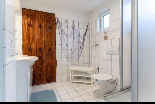 a bathroom with a toilet and a wooden door at Haus Laffina in Büsum