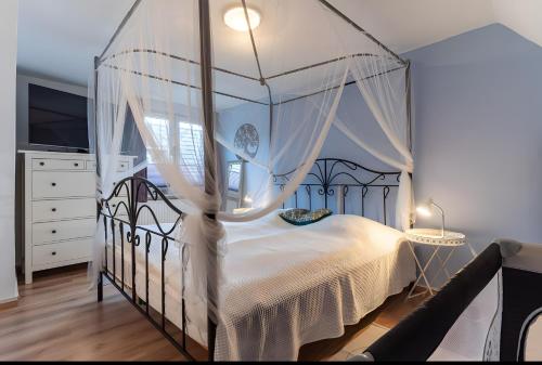 a bedroom with a canopy bed with white curtains at Haus Laffina in Büsum