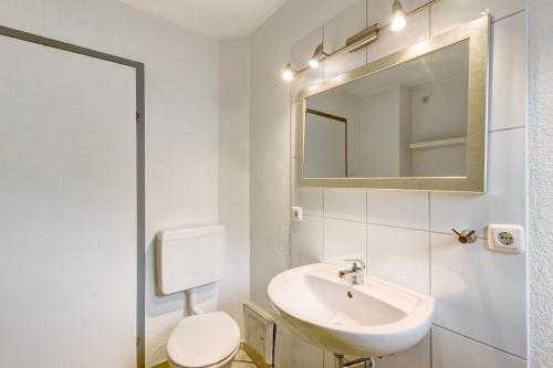 a bathroom with a sink and a toilet and a mirror at Ferienwohnung Wallisch in Schotten