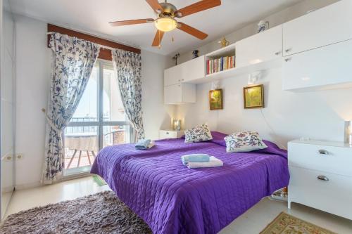 a purple bed in a room with a window at Apartamento Lance del Sol in Fuengirola