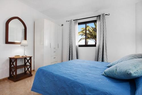 a bedroom with a blue bed and a window at La Casa De Los Sueños in Corralejo