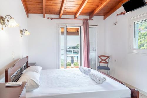 a white bedroom with a bed and a window at Alex bar apartments in Parga