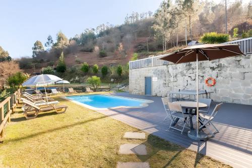 a patio with a table and an umbrella and a pool at Casa de Balinhas - Gerês in Ventosa