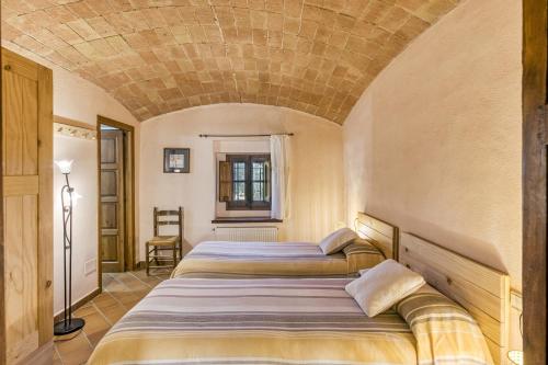 two beds in a room with a stone ceiling at Can Palau in Agullana