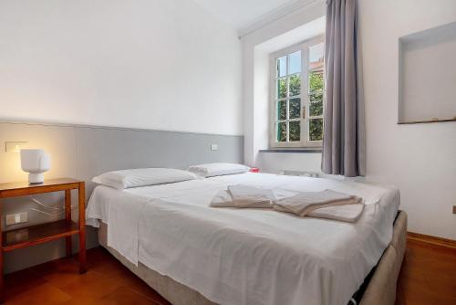 a white bed in a room with a window at Via Colombo 12 - Trilocale in Bonassola