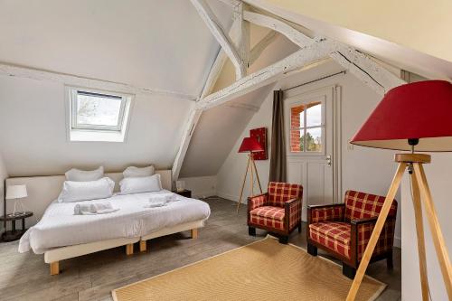 a bedroom with a bed and two chairs at Les Ecuries - La Trigalière in Ambillou