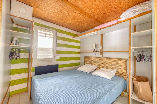 a small bedroom with green and white stripes at Chalet A Village Vacances in Gujan-Mestras