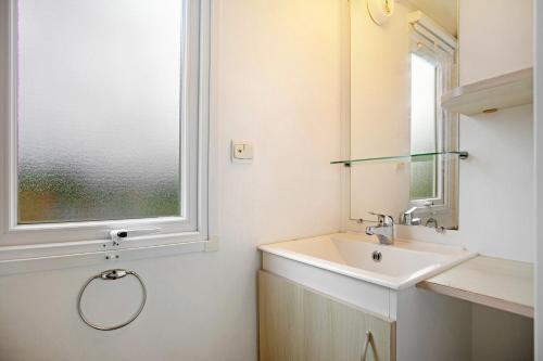 a bathroom with a sink and a window at Bungalow T3 i i i - 15 Min Nazaré in Pataias