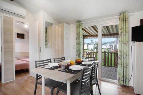 a dining room with a table and chairs and a balcony at Bungalow T3 i i i - 15 Min Nazaré in Pataias