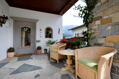 a patio with a table and chairs and a stone wall at Haus Friederike - Sylvia Brunner in Ellmau