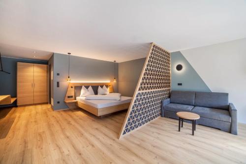 a hotel room with a bed and a couch at Aktiv Lodge Meran - Garden Two in San Martino