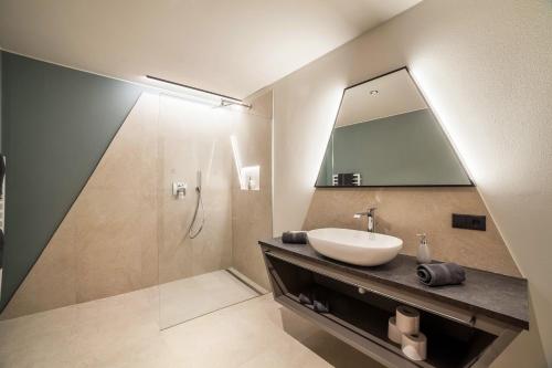 a bathroom with a sink and a shower with a mirror at Aktiv Lodge Meran - Garden Two in San Martino