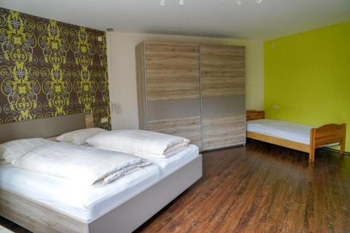 a bedroom with two beds with green walls and wooden floors at Ferienwohnung Roth in Frickingen