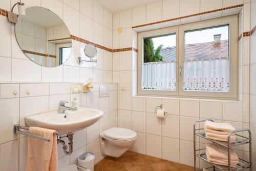 a bathroom with a sink and a toilet and a window at Ferienhaus Behler in Kressbronn am Bodensee