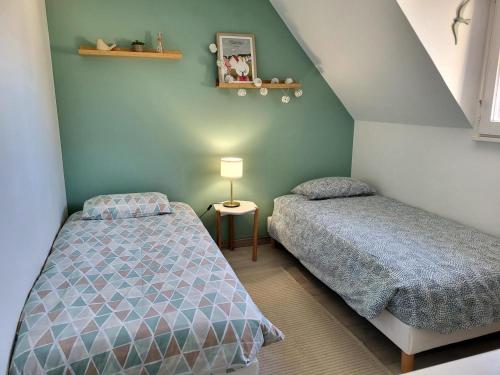 a bedroom with two beds and a table with a lamp at Maison De Plage Le Cocon Pirouais in Pirou