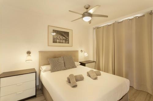 a bedroom with a white bed with a ceiling fan at Apartamento Yumbo Maspalomas in Maspalomas