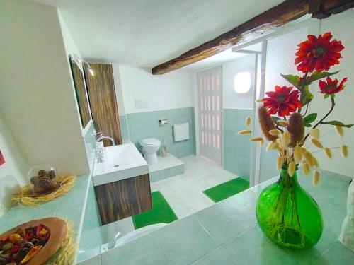 a green vase with flowers on a counter in a bathroom at Nel Cuore della Via Francigena in Aosta