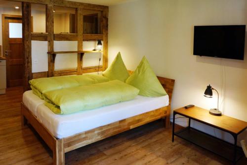 a bedroom with a bed with green pillows and a television at Urlaub Im Kulturdenkmal in Alpirsbach