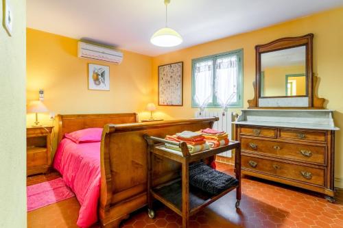 a bedroom with a bed and a dresser and a mirror at La Tonnelle, clim, jardin in Malaucène
