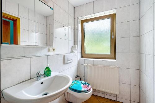 a bathroom with a sink and a toilet and a window at Hotel Neue Krone - Markt Erlbach in Markt Erlbach