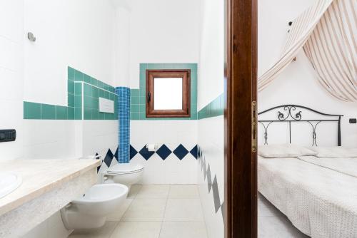 a bathroom with a toilet and a sink and a bed at Villa Pedduzza in Orosei