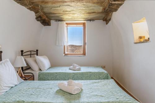 two beds in a room with a window at Archontiko Keli in Katákoilos