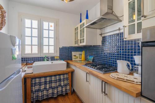 eine Küche mit blauen Fliesen an der Wand und einem Waschbecken in der Unterkunft La Presqu'ile in Talmont