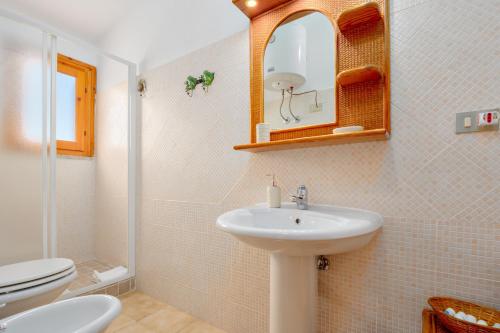 a bathroom with a sink and a toilet and a mirror at Casa Asfodeli in San Teodoro