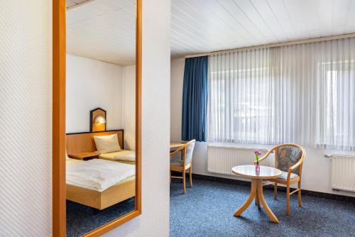 a hotel room with a bed and a table and a mirror at Gasthaus, Hotel am Dreienberg in Friedewald
