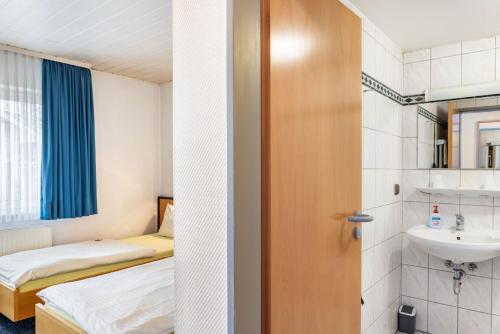 a bathroom with two beds and a sink at Gasthaus, Hotel am Dreienberg in Friedewald