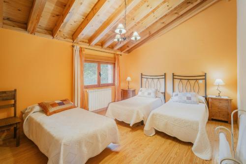 two beds in a room with yellow walls and wooden ceilings at Los Molinillos in Caballar