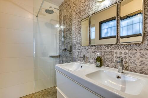 a bathroom with a sink and a mirror and a shower at Sublime Maison Moderne avec piscine in Mauguio