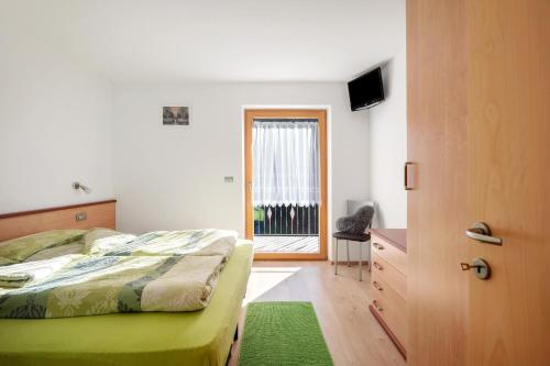 a bedroom with a bed and a door with a window at Innerjerberhof Neiderseit in Lauregno