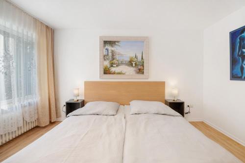 a bedroom with a large white bed with two lamps at Haus Annenberg in Monzelfeld