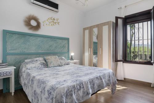 a bedroom with a bed with a blue and white blanket at Finca Arroyuelo in Prado del Rey