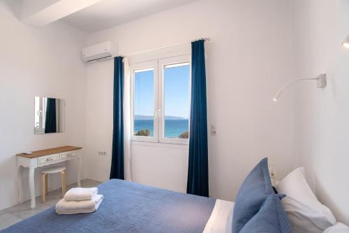a bedroom with a blue bed and a window at Punda Beach Seaside Retreat in Kampos Paros