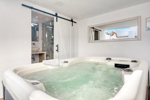 a white bathroom with a large tub with green water at Denia Beach Lodge in Denia