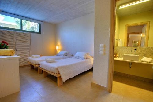 a bedroom with two beds and a sink and a mirror at Villa Linatela Ideales Resort in Kefallonia
