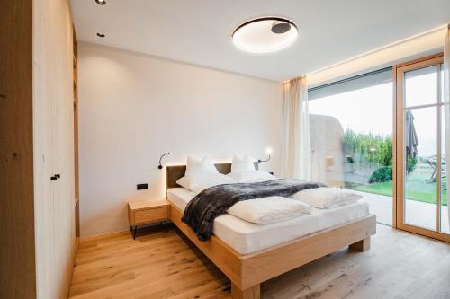 a bedroom with a bed and a large window at Valentinerhof Apt Terra in San Michele