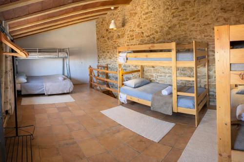 a room with bunk beds in a stone wall at Masia Sa Calma - La Tribu in Susqueda