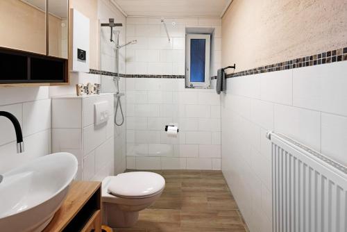 a white bathroom with a toilet and a sink at Ferienwohnung Krummel in Edertal