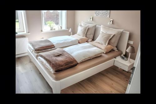 a bedroom with a large white bed with pillows at Ferienhaus Nanny Und Helene in Uphusum