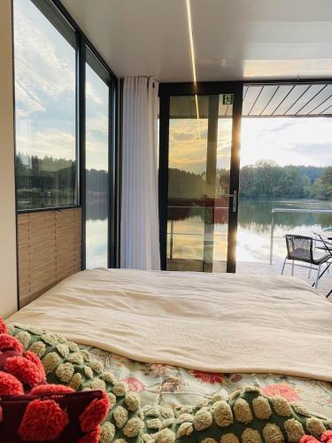ein großes Bett in einem Zimmer mit einem großen Fenster in der Unterkunft Hausboot Eisvogel in Kirchberg an der Raab