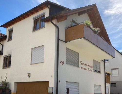 a white building with a balcony on top of it at Ferienwohnungen Hubertus in Metzingen